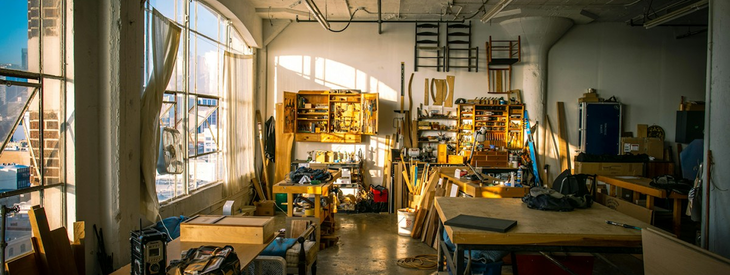 Sunlit furniture workshop with worktables, tools and timber