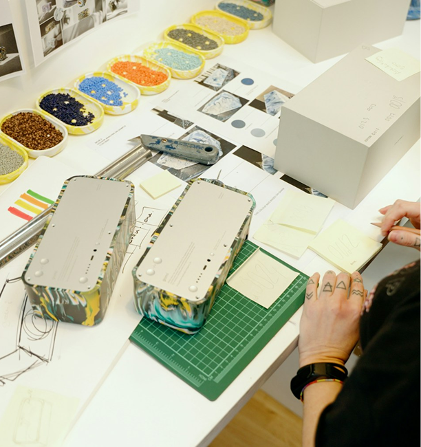 Designer sketching at a worktable with material samples and colour palettes